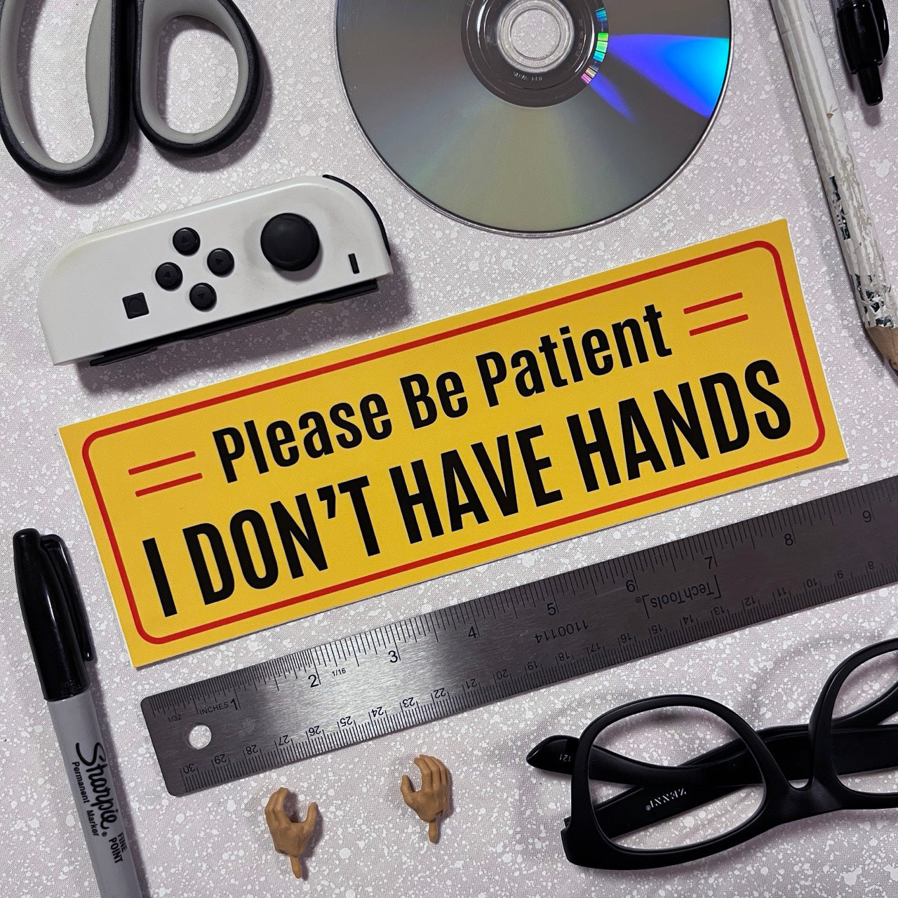 Yellow bumper sticker with Please Be Patient I Don't Have Hands text