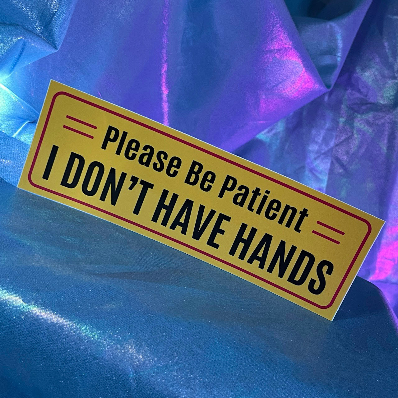 Yellow bumper sticker with Please Be Patient I Don't Have Hands text