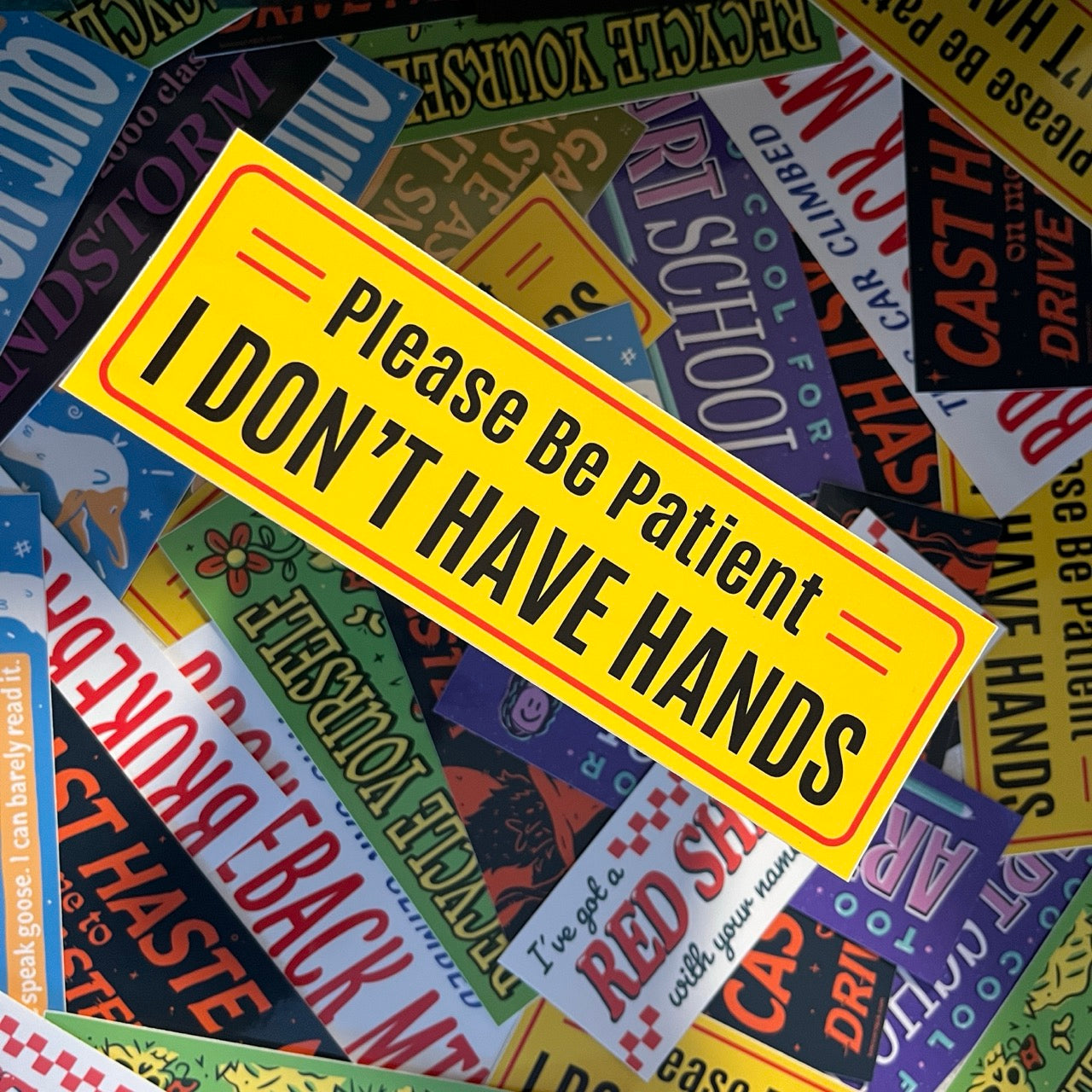 Yellow bumper sticker with Please Be Patient I Don't Have Hands text